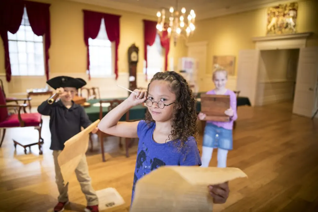 Children in a historical setting engaging in a playful Boston scavenger hunt activity.