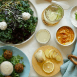 A spread of assorted dishes including salads, sauces, and garnishments, featuring fresh ingredients and vibrant colors.