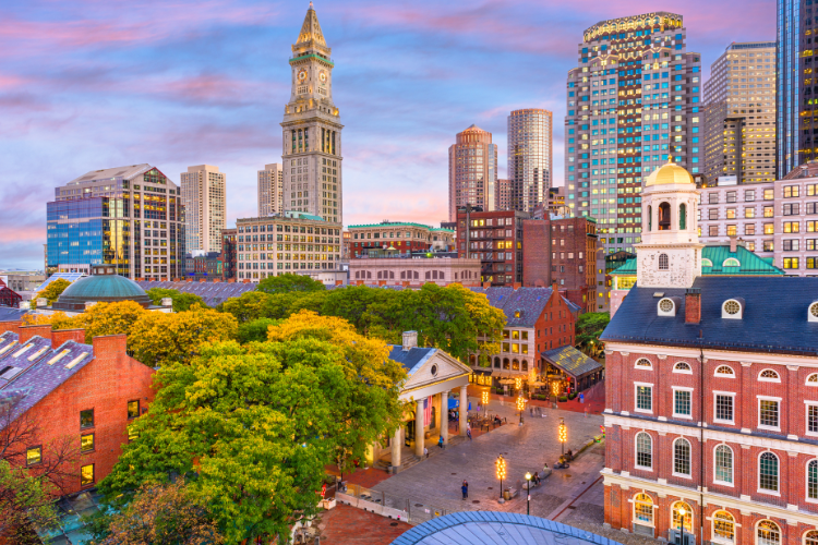 A vibrant cityscape featuring historical buildings and modern skyscrapers, likely Boston with Faneuil Hall and the Custom House Tower.