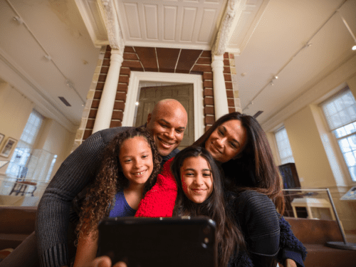 A family is happily taking a selfie together in an indoor setting.