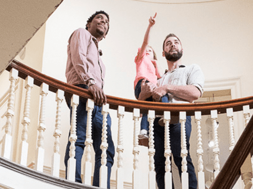 People standing on a spiral stairwell, one person pointing upwards.