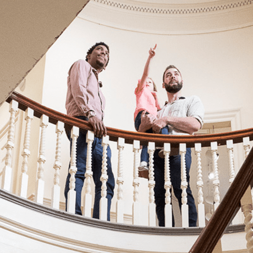 People standing on a spiral stairwell, one person pointing upwards.