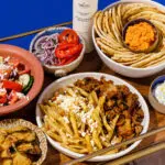 An assortment of Mediterranean dishes, including pasta, salad, pita bread, and dips.