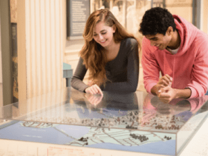 Two people looking at a museum display featuring a topographic map or model.