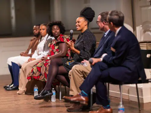 A panel of six people is seated on stage, engaging in a discussion.