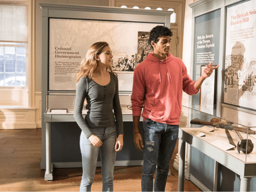 Two people are observing exhibits in a historical museum. Keywords: boston historical sites, old state house