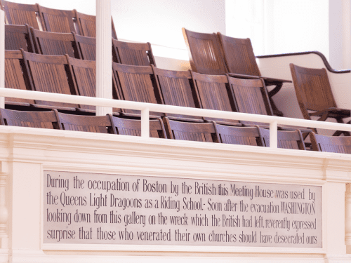 Seating with a historical plaque about the use of a Boston meeting house during British occupation.