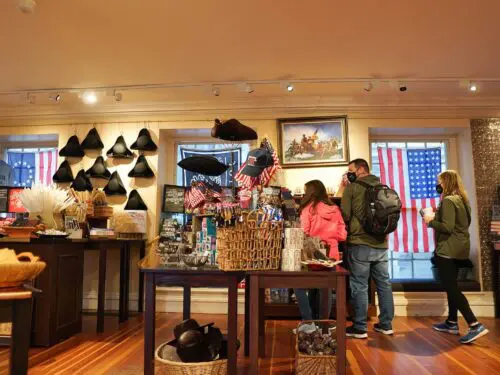 A gift shop with American flags, historical hats, and visitors inside.