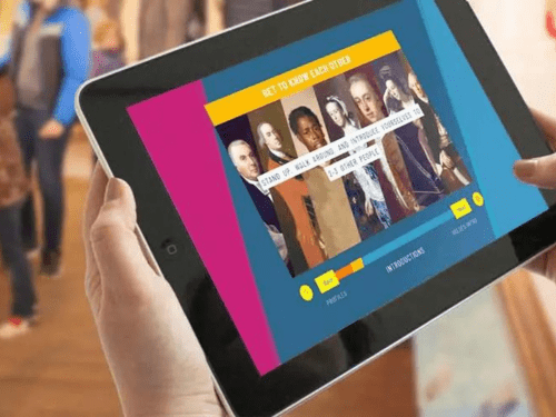 A person is holding a tablet displaying a museum interactive app with paintings.