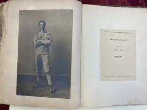 Open book displaying a vintage photograph of a man in uniform beside a title page.