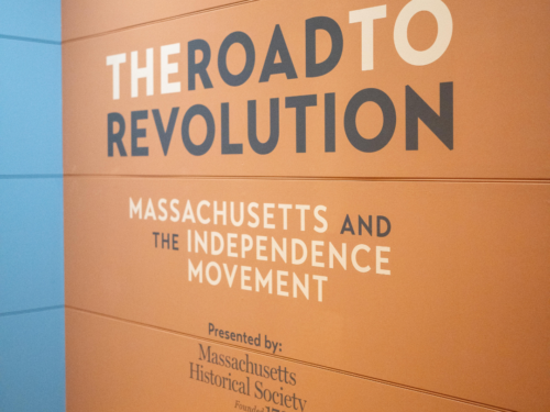 Exhibit wall with text saying "The Road to Revolution: Massachusetts and the Independence movement" presented by Massachusetts Historical Society founded 1971
