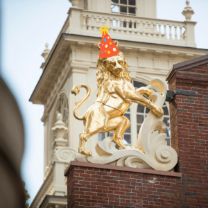 Gilded lion statue with photoshopped party hat