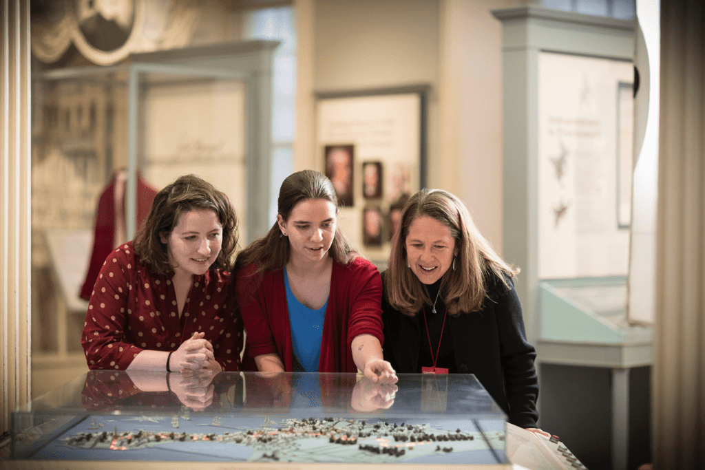 Three people examining a museum exhibit with interest.